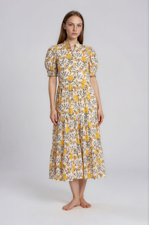 Woman wearing a floral dress with yellow and white flowers on a plain background