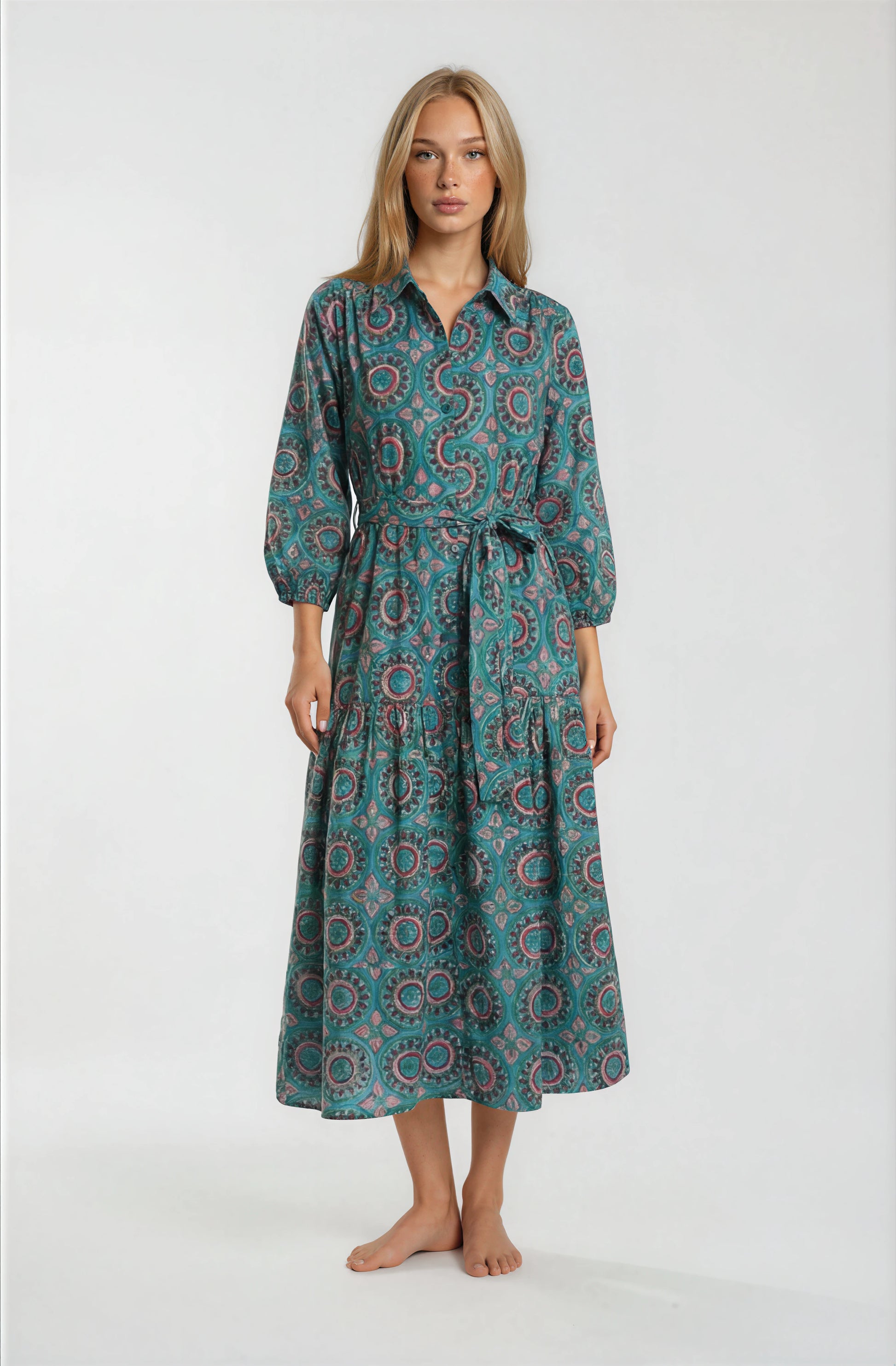 Woman wearing a patterned teal dress on a white background