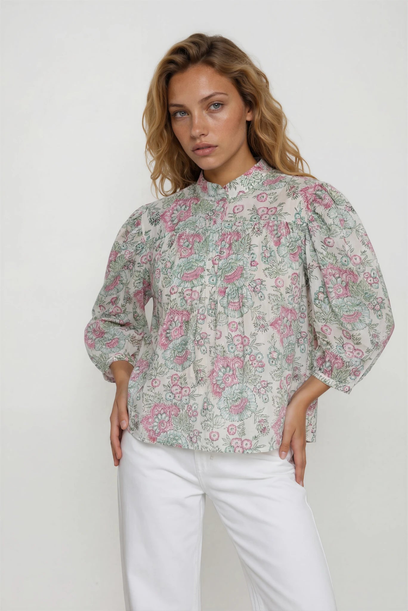 Woman wearing a floral blouse with puffed sleeves against a white background