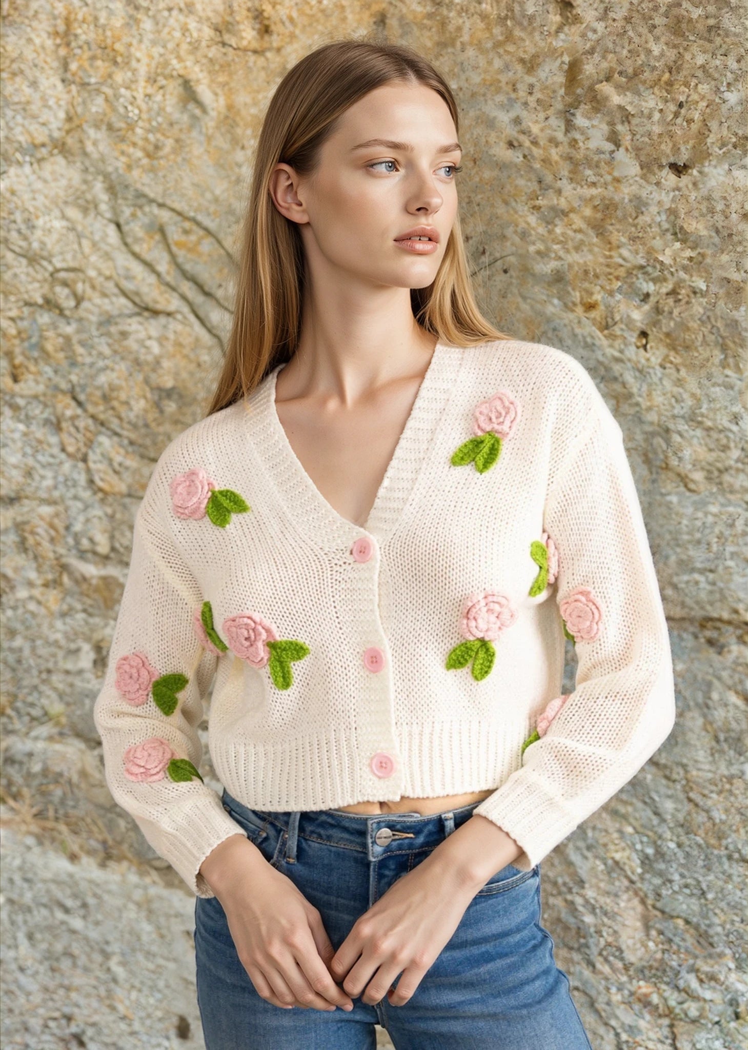 A woman wearing a white sweater with floral embroidery, paired with blue jeans.